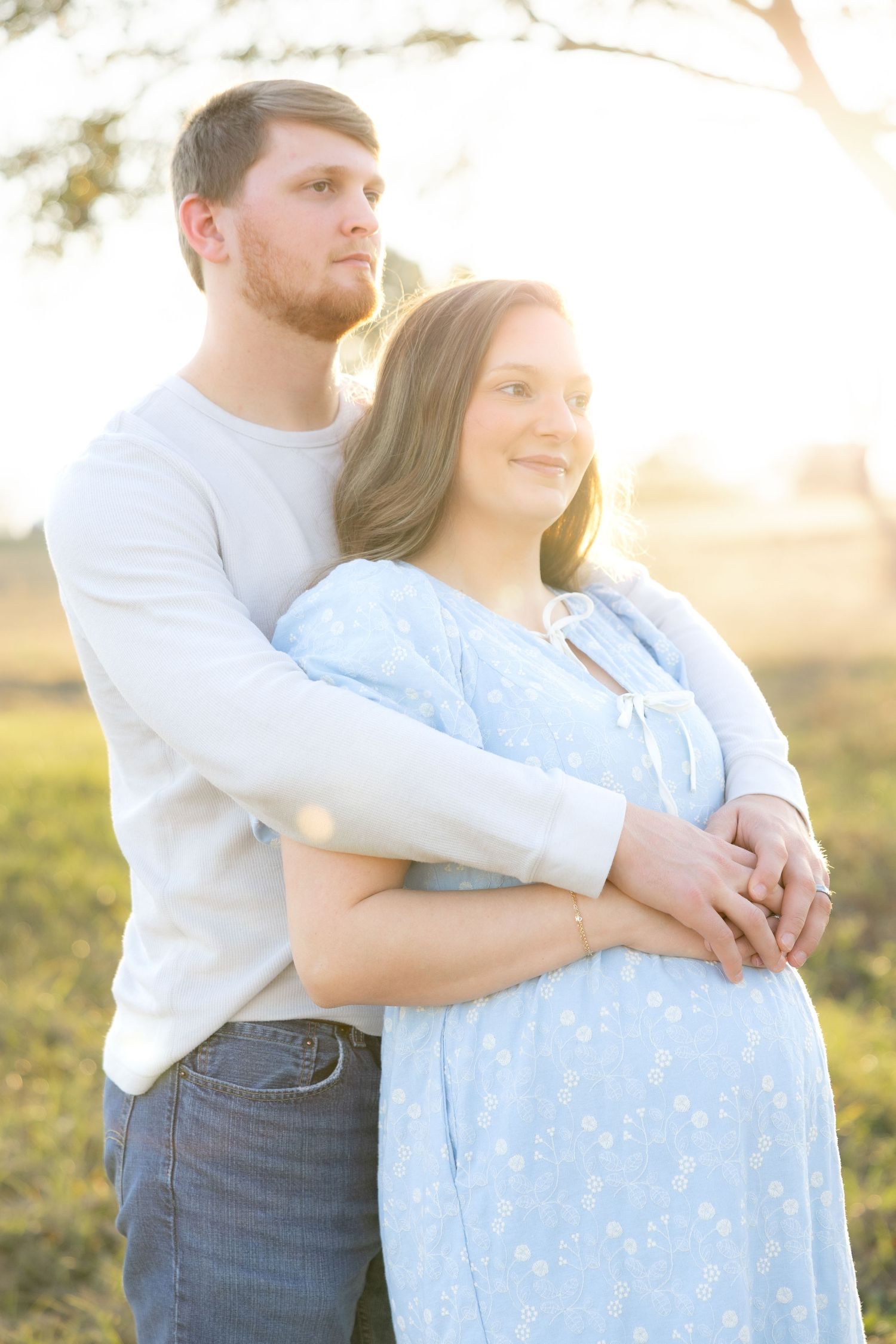 Expecting couple holding each other in a field at sunset in Dothan, Alabama