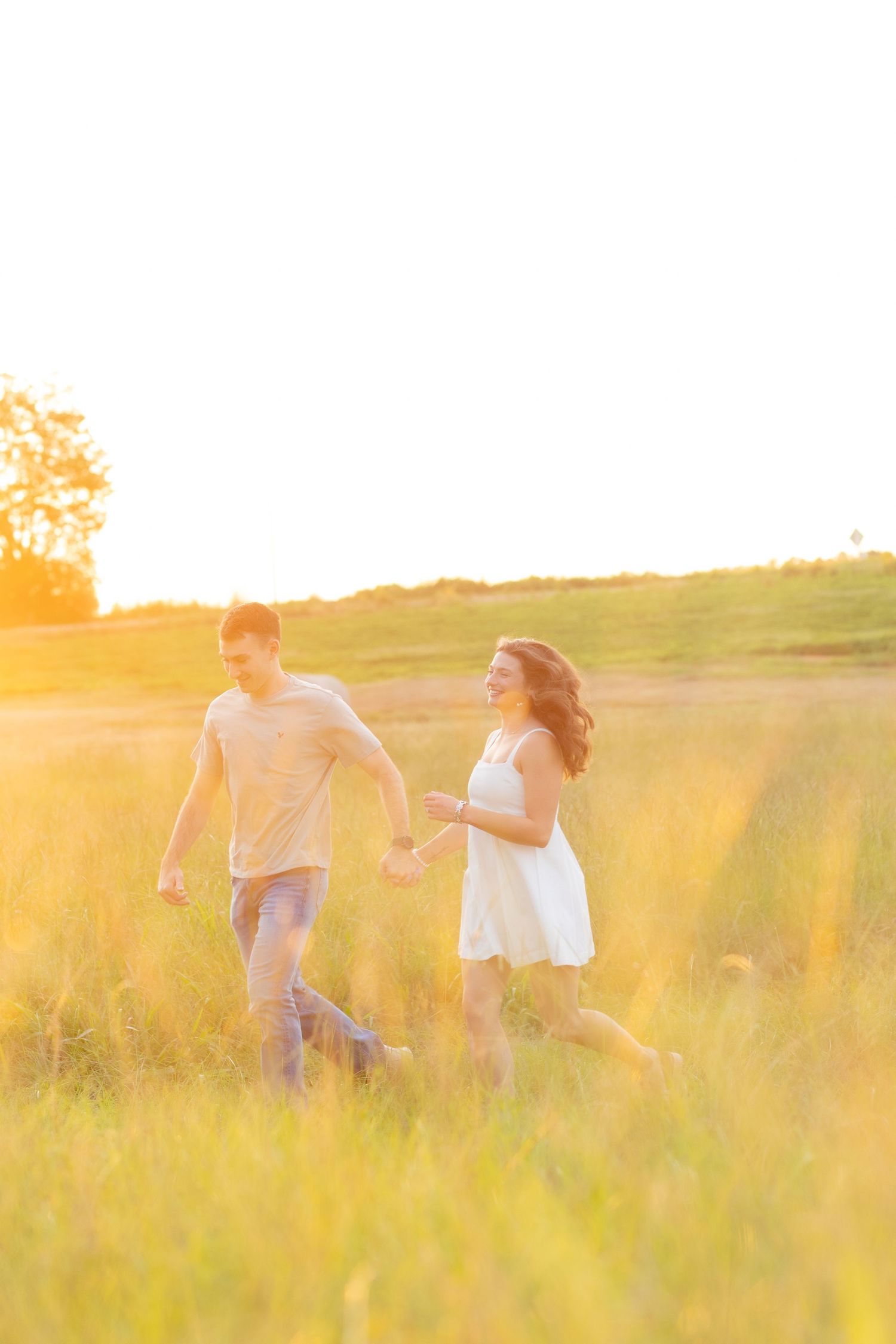 Couple running through a grass field at sunset in Dothan, Alabama