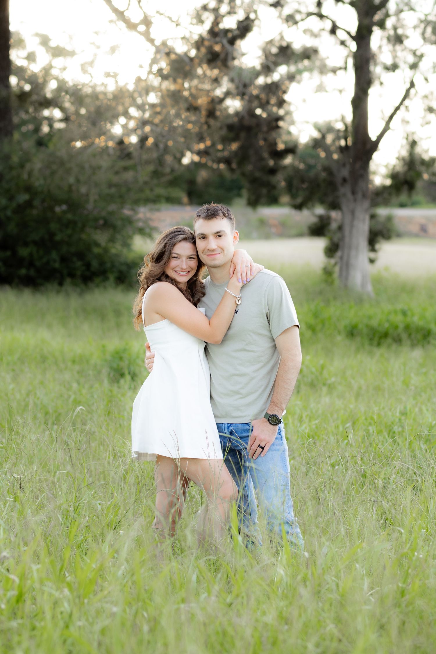 Couple hugging in a grass field at sunset in Dothan, Alabama