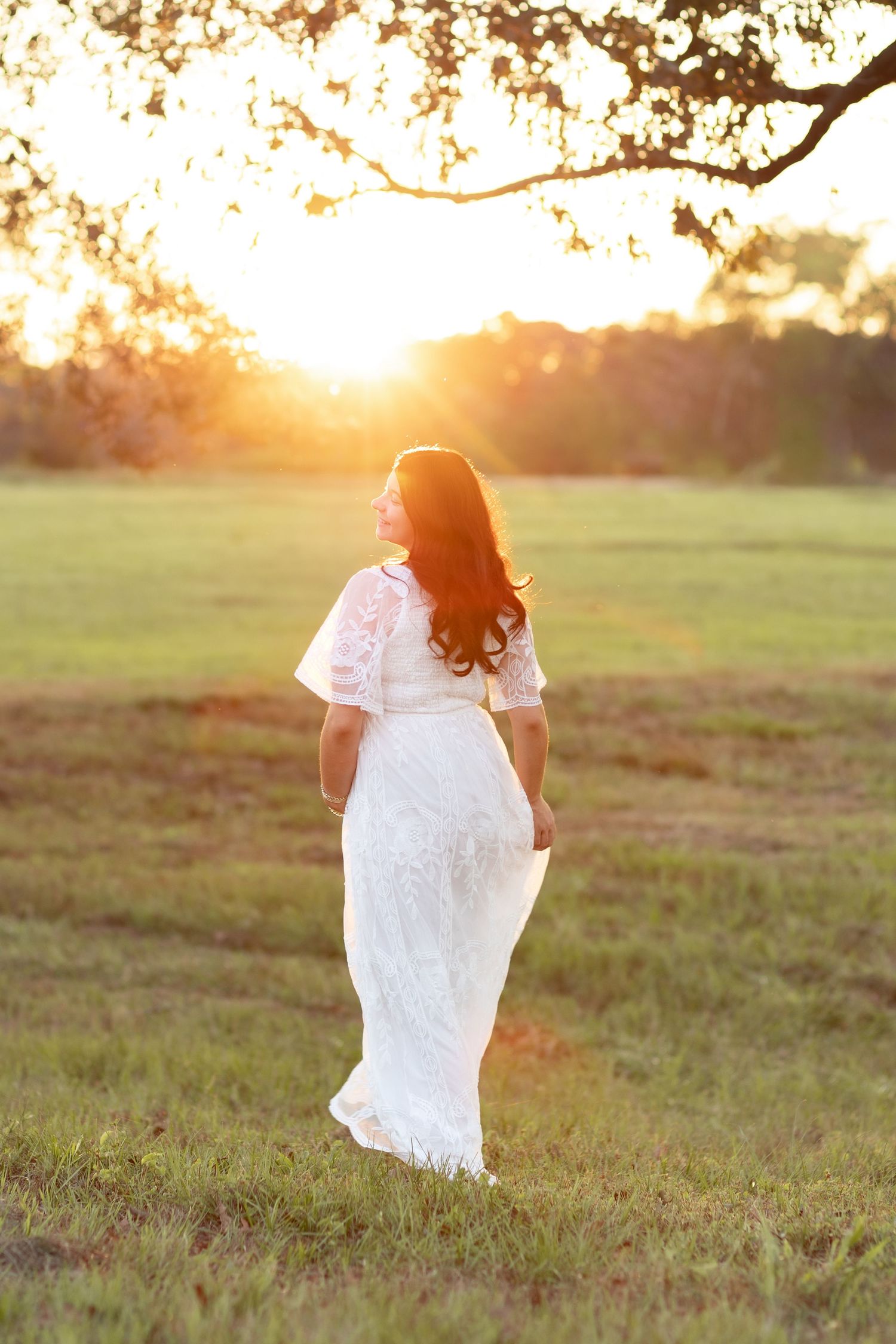 Expecting mother dancing in a grass field at sunset in Dothan, Alabama