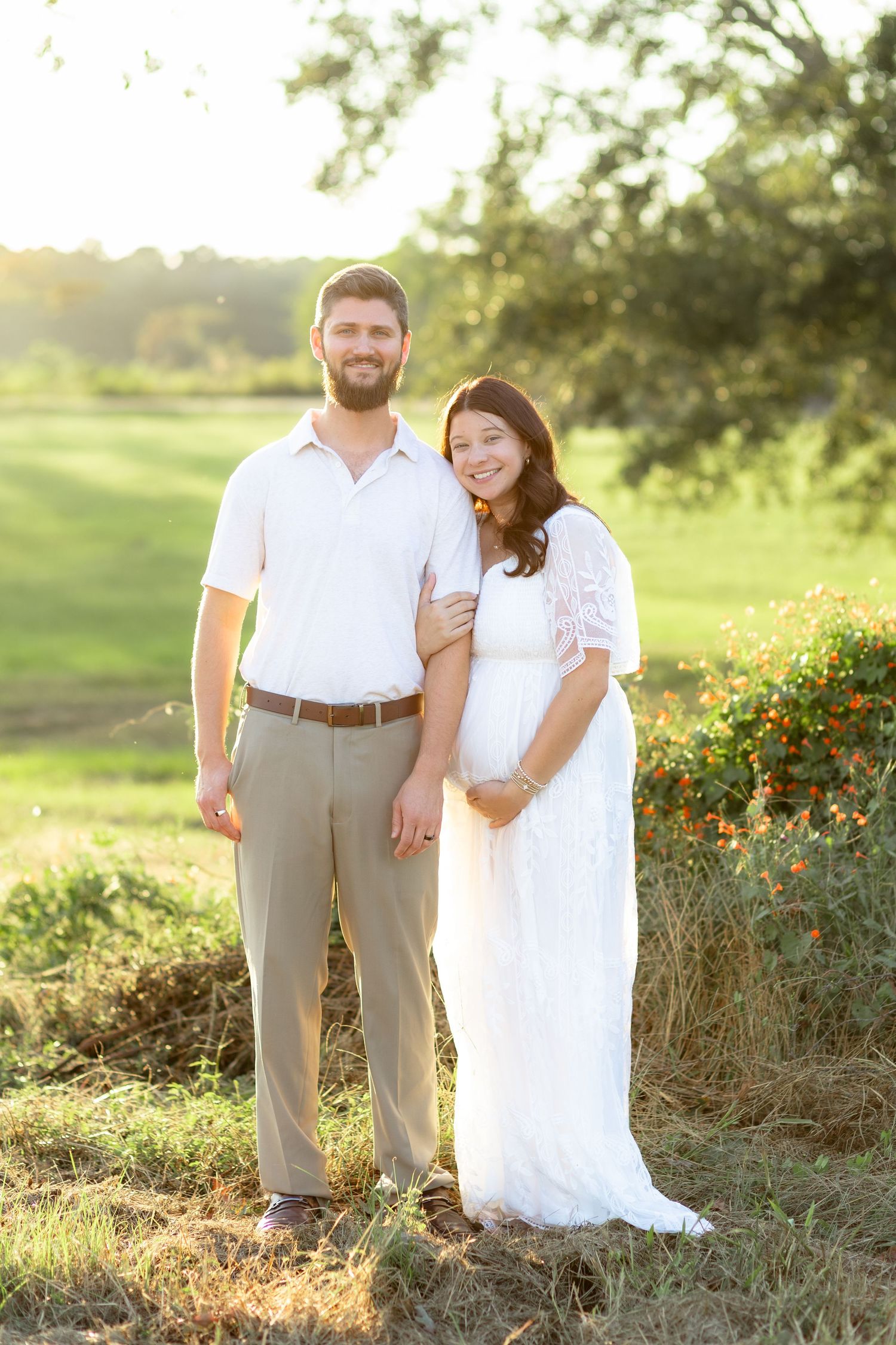 Expecting couple holding each other in a grass field at sunset in Dothan, Alabama