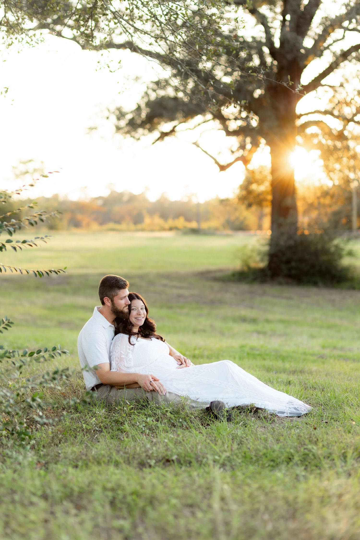 Expecting couple holding each other in a grass field at sunset in Dothan, Alabama