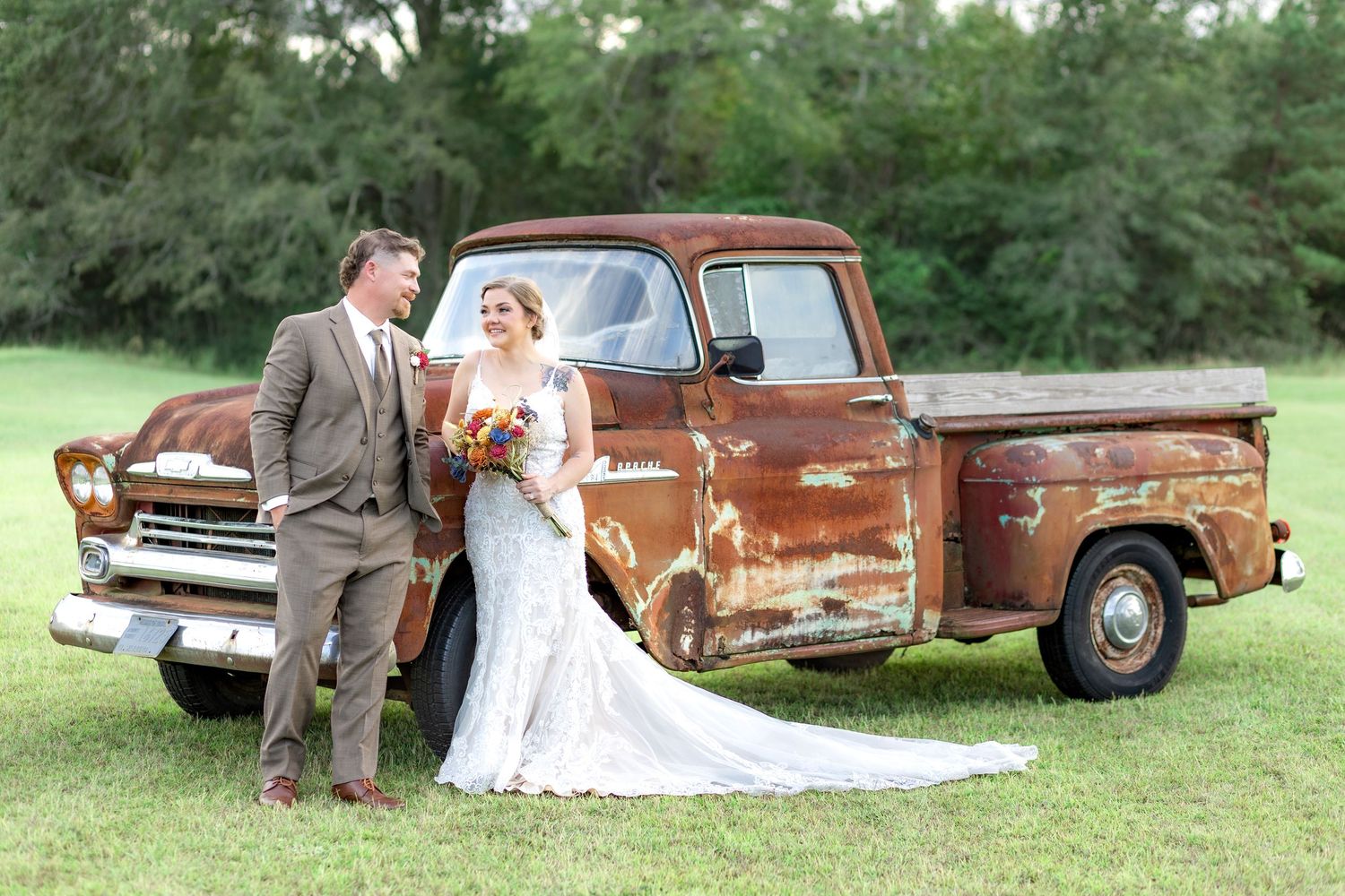 Bride and groom pose in front of a rustic chevy at sunset at Hilltop Acres Wicksburg, Alabama