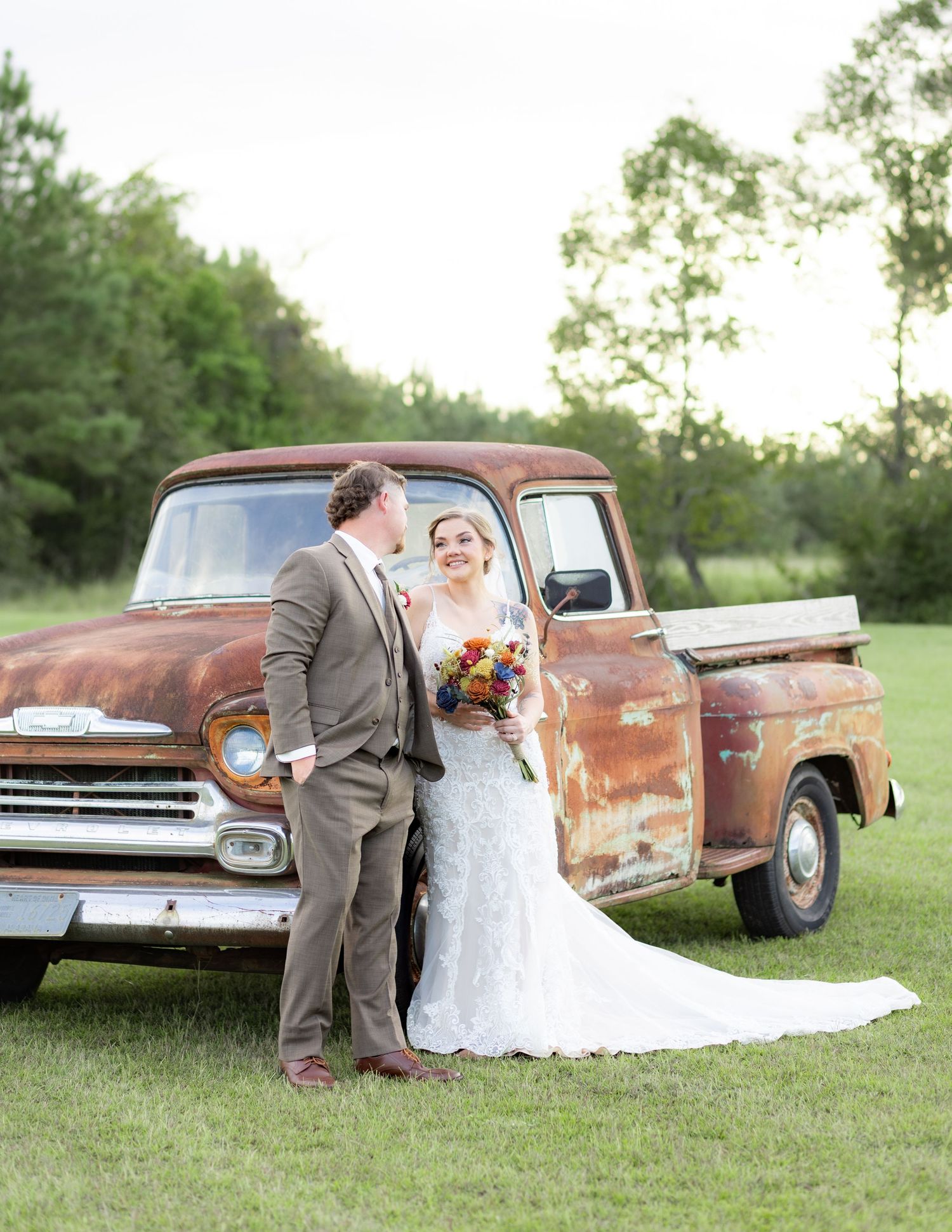 Bride and groom pose in front of a rustic chevy at sunset at Hilltop Acres Wicksburg, Alabama