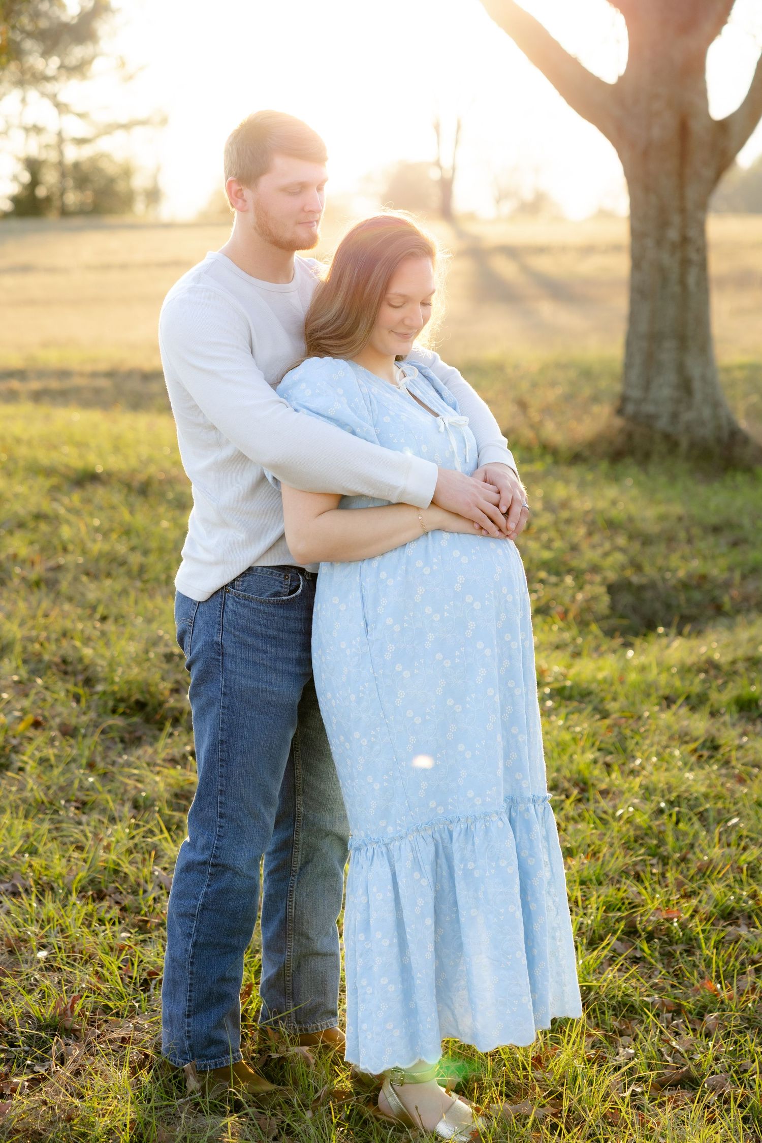Expecting couple holding each other in a field at sunset in Dothan, Alabama