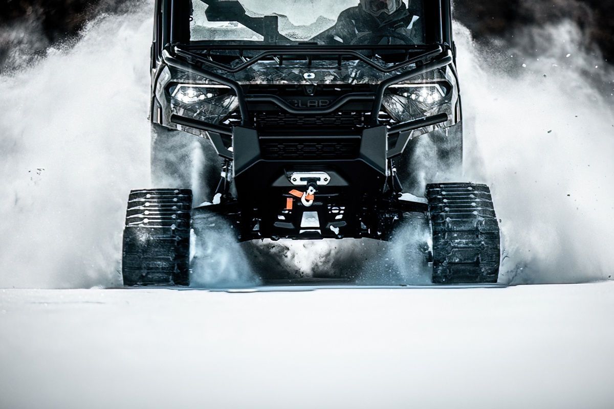 Off-road vehicle kicking up snow while driving through winter terrain.