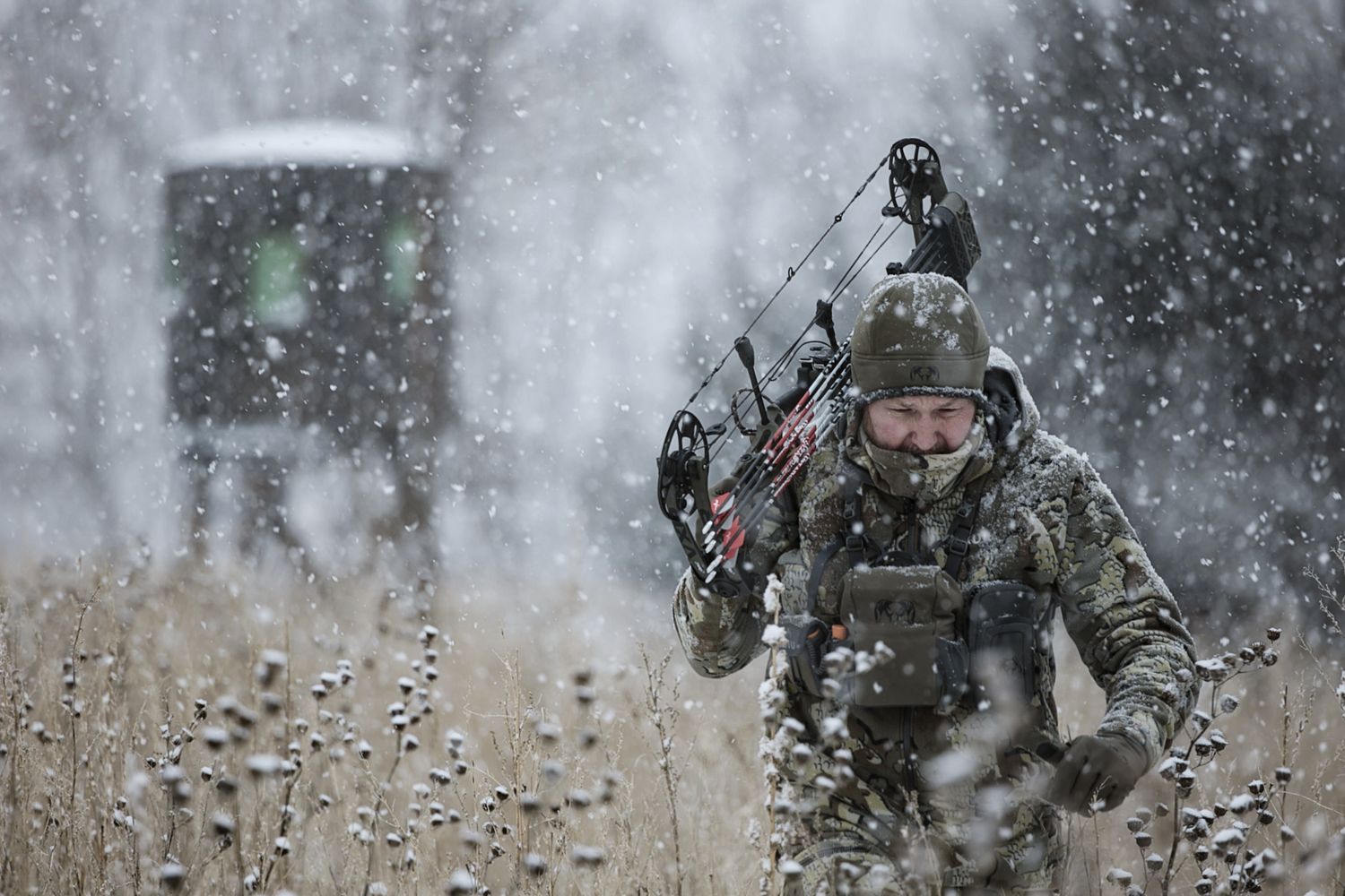 A camouflaged hunter moves through snowy conditions with tactical gear.