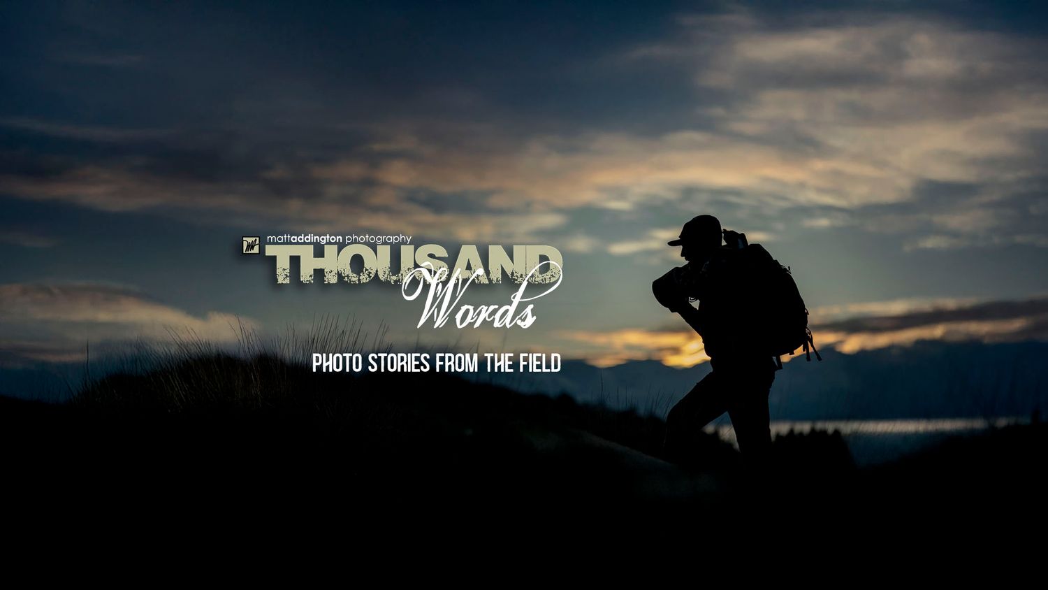 A silhouetted photographer captures dramatic sunset photos against a moody dark clouded sky.