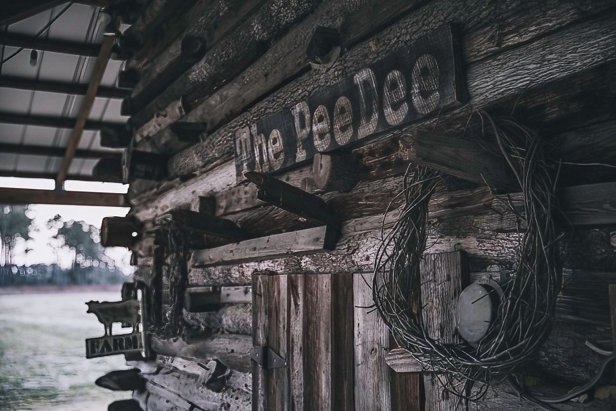 Rustic log cabin exterior with weathered wooden sign and vintage details.