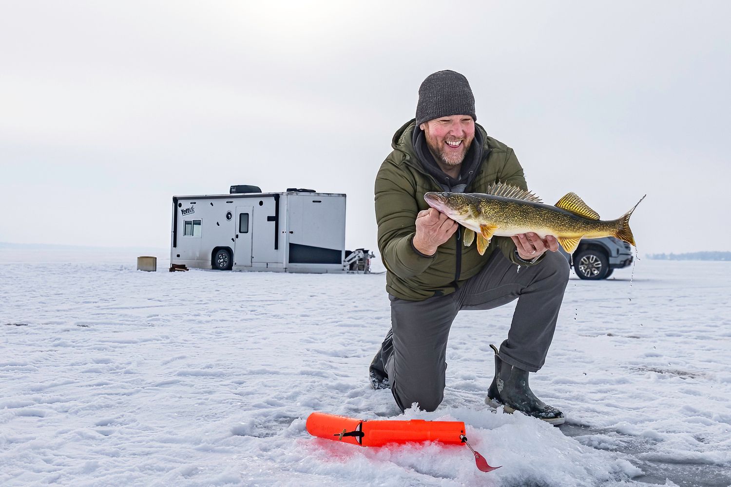Ice fishing setup with portable shelter and equipment on a snow-covered frozen lake.