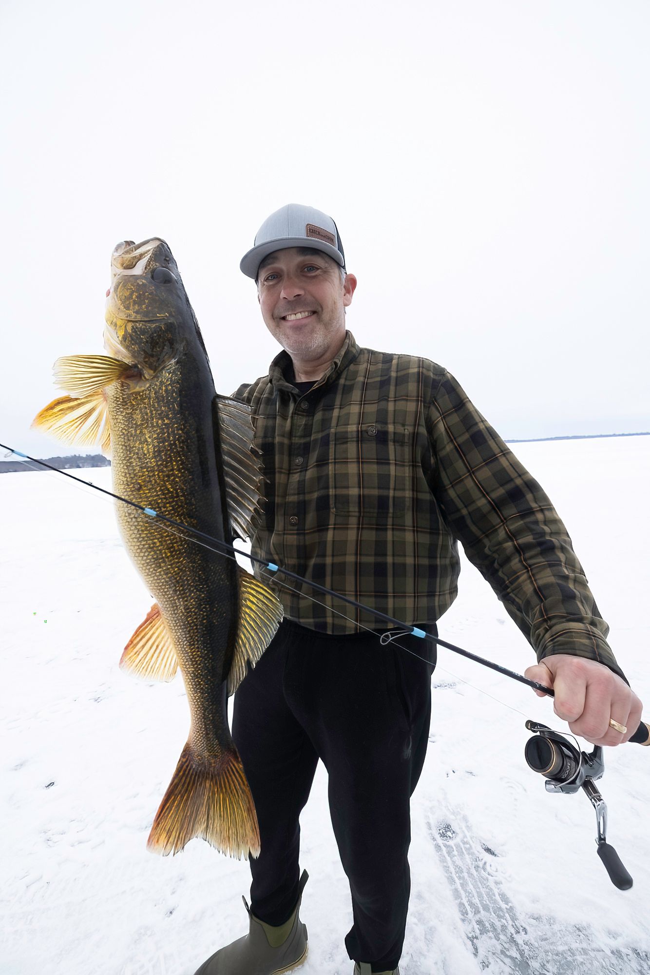 Winter angler shows off a trophy-sized walleye caught while ice fishing.