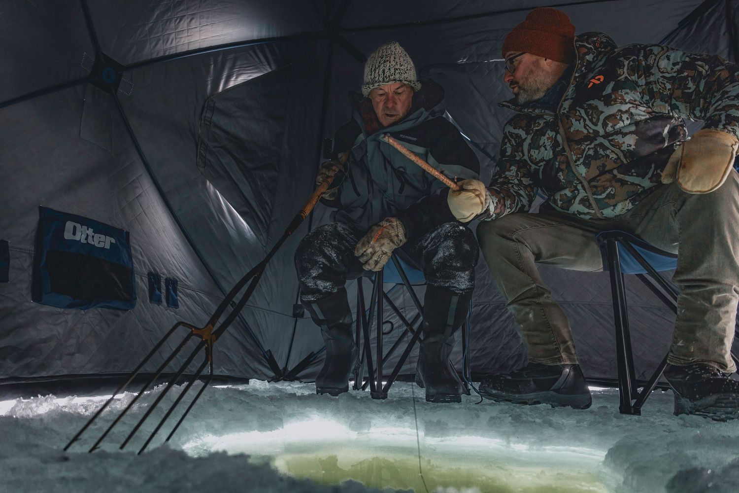 Ice fishing spearing scene with equipment and holes drilled in frozen lake surface.