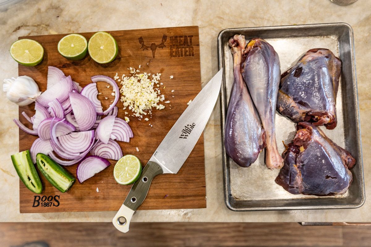 Food prep with chopped onions, limes and knife on wooden cutting board.