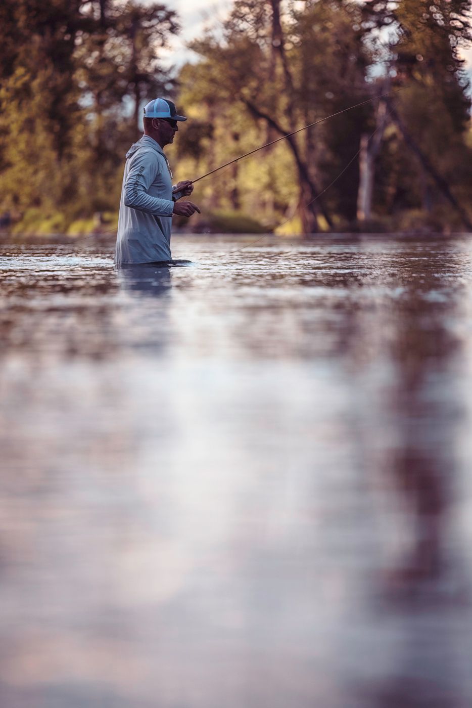 Misty morning fishing scene on calm lake with soft golden light.
