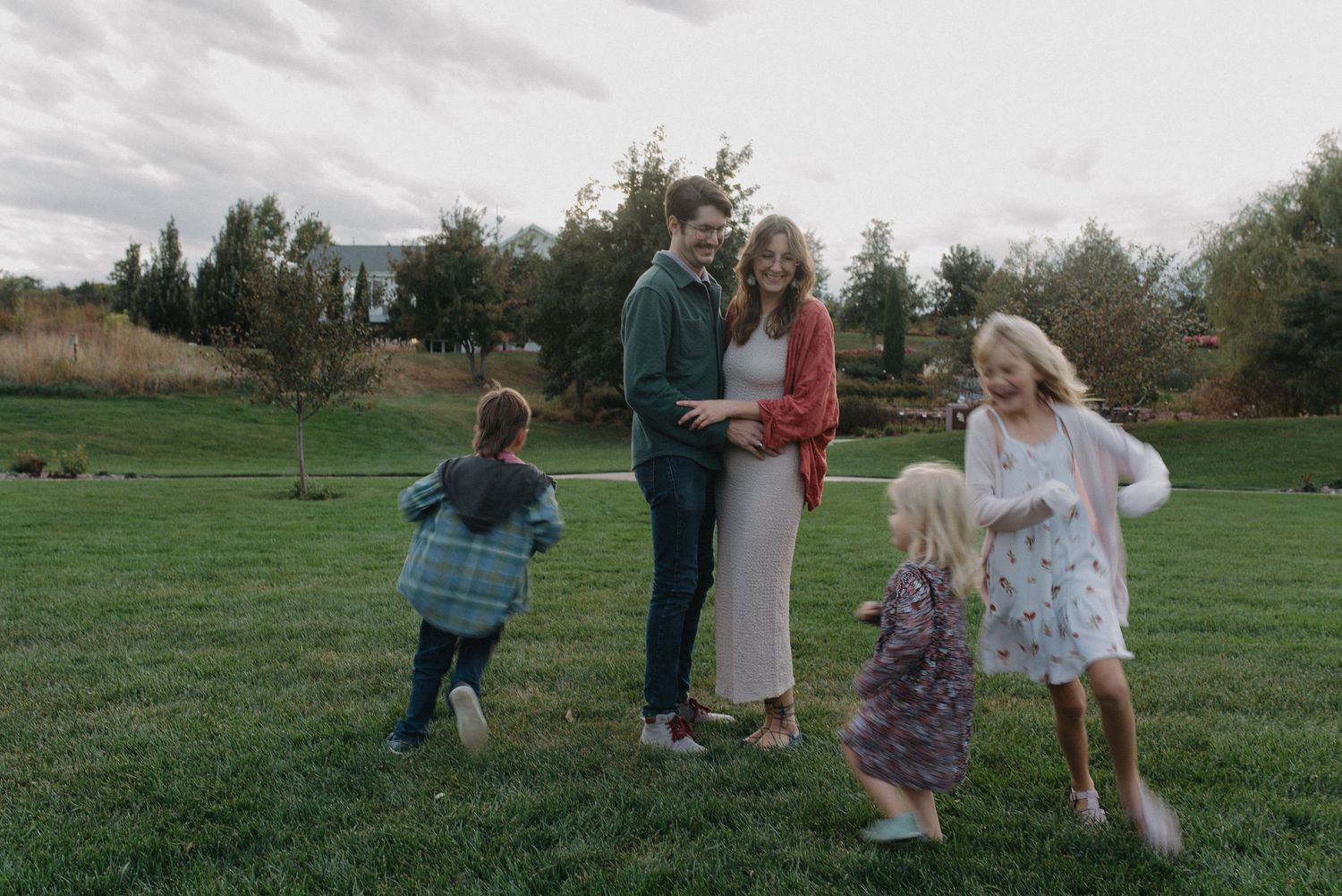 Family gathering on a grassy lawn as children run toward their parents.