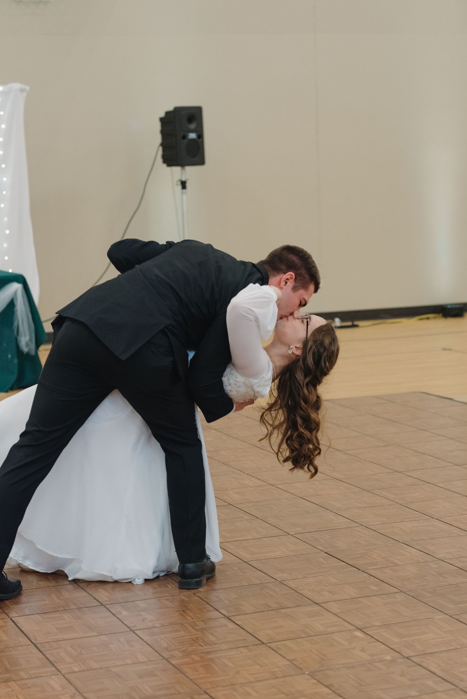 Bride and groom sharing a romantic dip kiss on the wedding dance floor during their first dance.