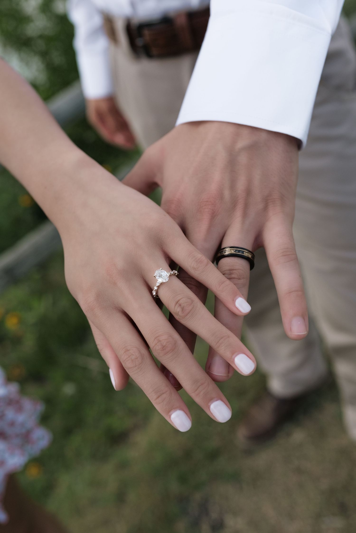 Close-up of engaged couple showing rings, woman with diamond ring and man with black band.