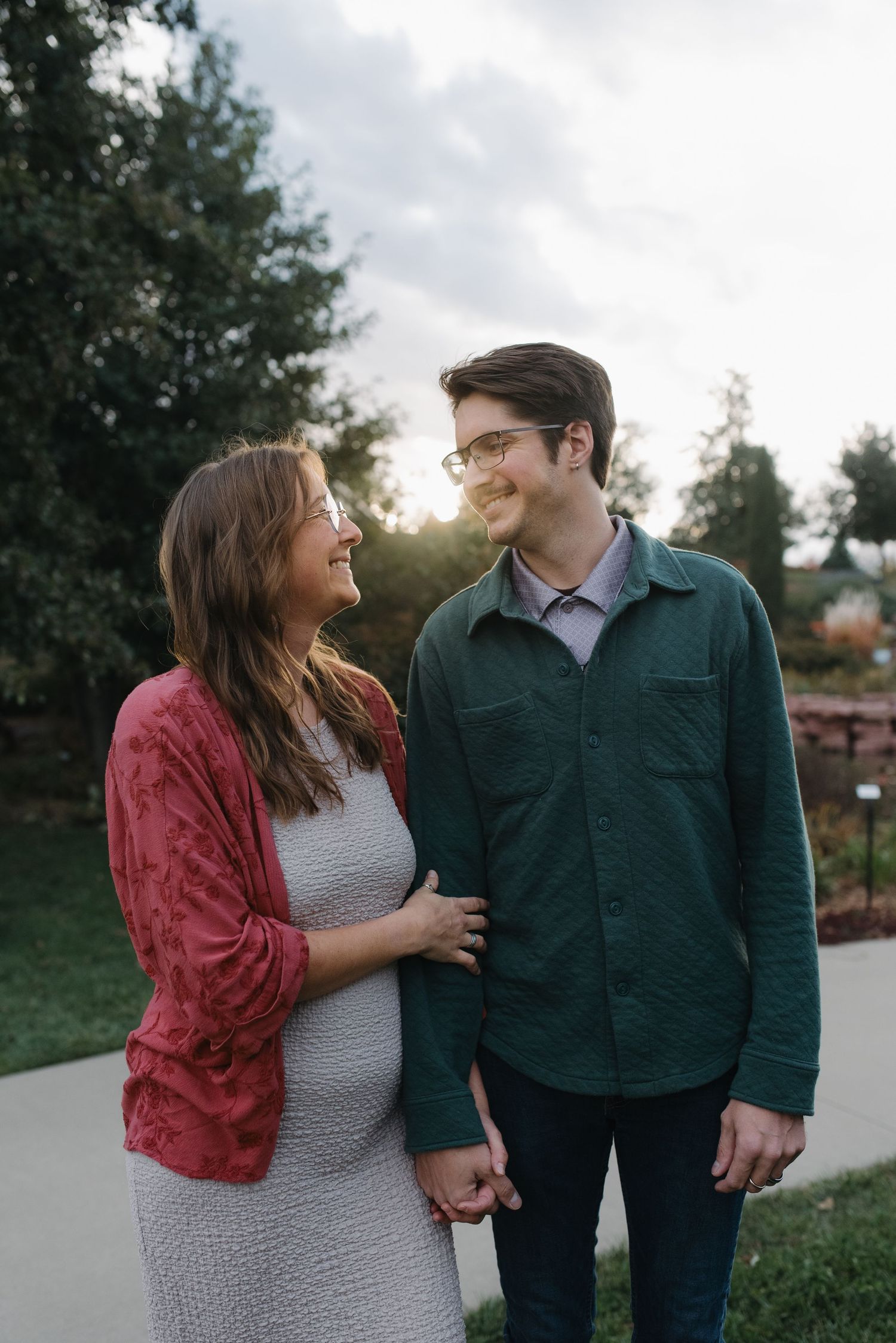 A couple gazes at each other lovingly while holding hands in a sunlit garden.