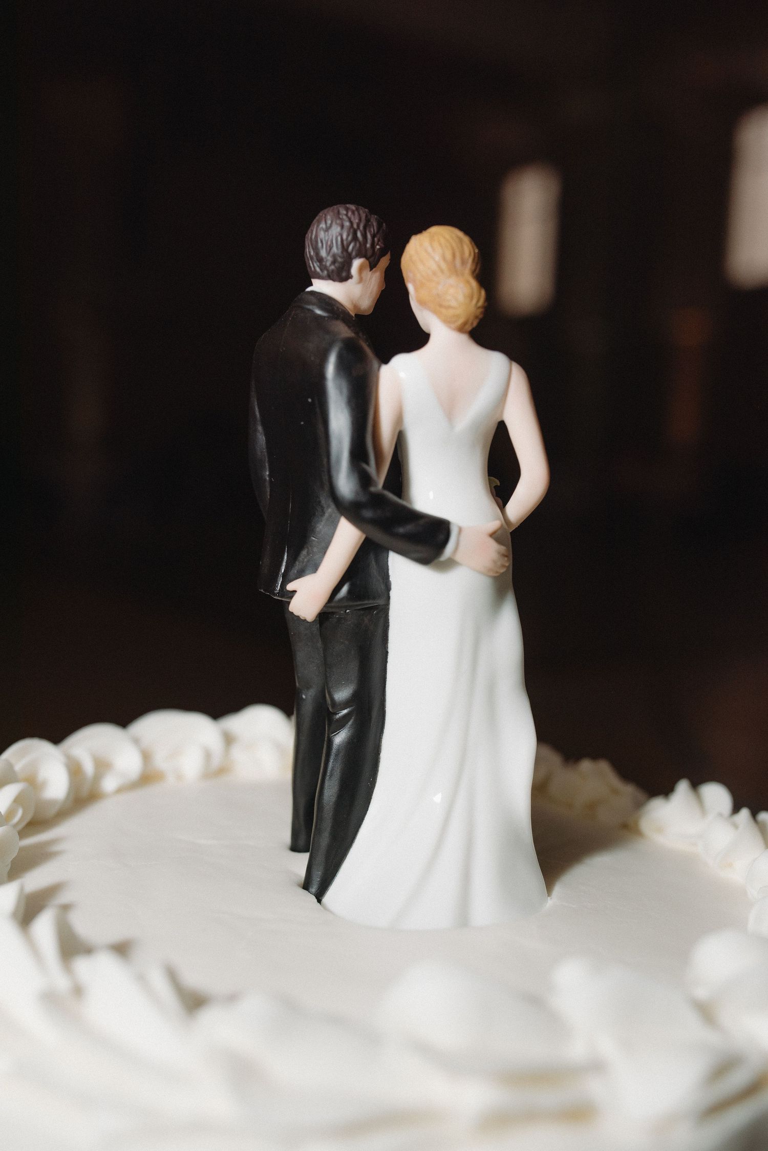 Classic wedding cake topper featuring bride and groom figurines standing together on white cake.