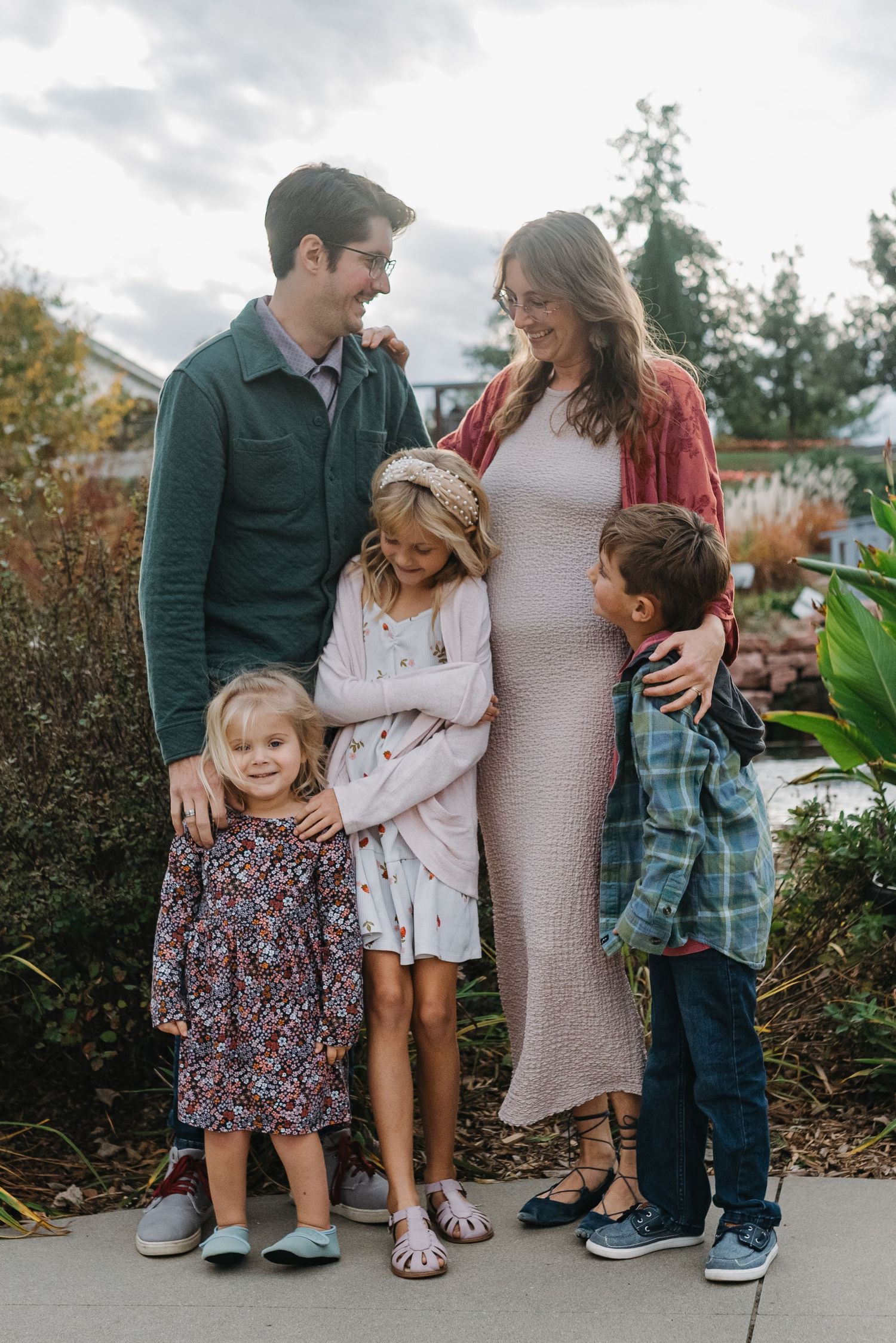 Joyful family of five laughing together outdoors in a vibrant fall garden setting.