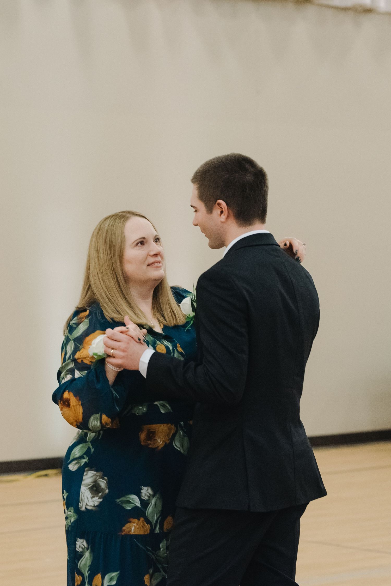 Mother and groom sharing a tender dance together at wedding reception in formal attire.