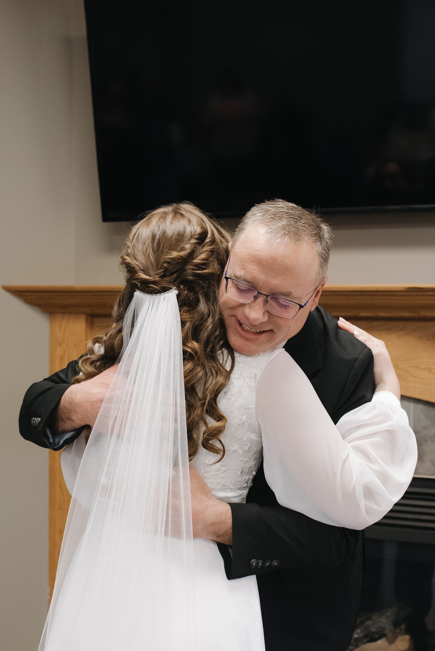 A bride and her father share a warm embrace during an emotional first look moment on her wedding day.