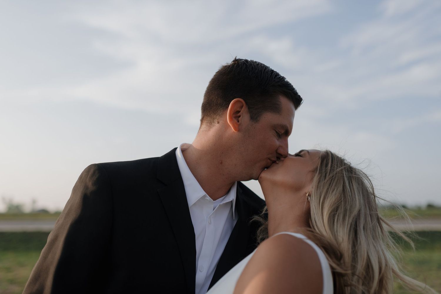 Close-up of a bride and groom sharing a kiss during their outdoor wedding photo session.