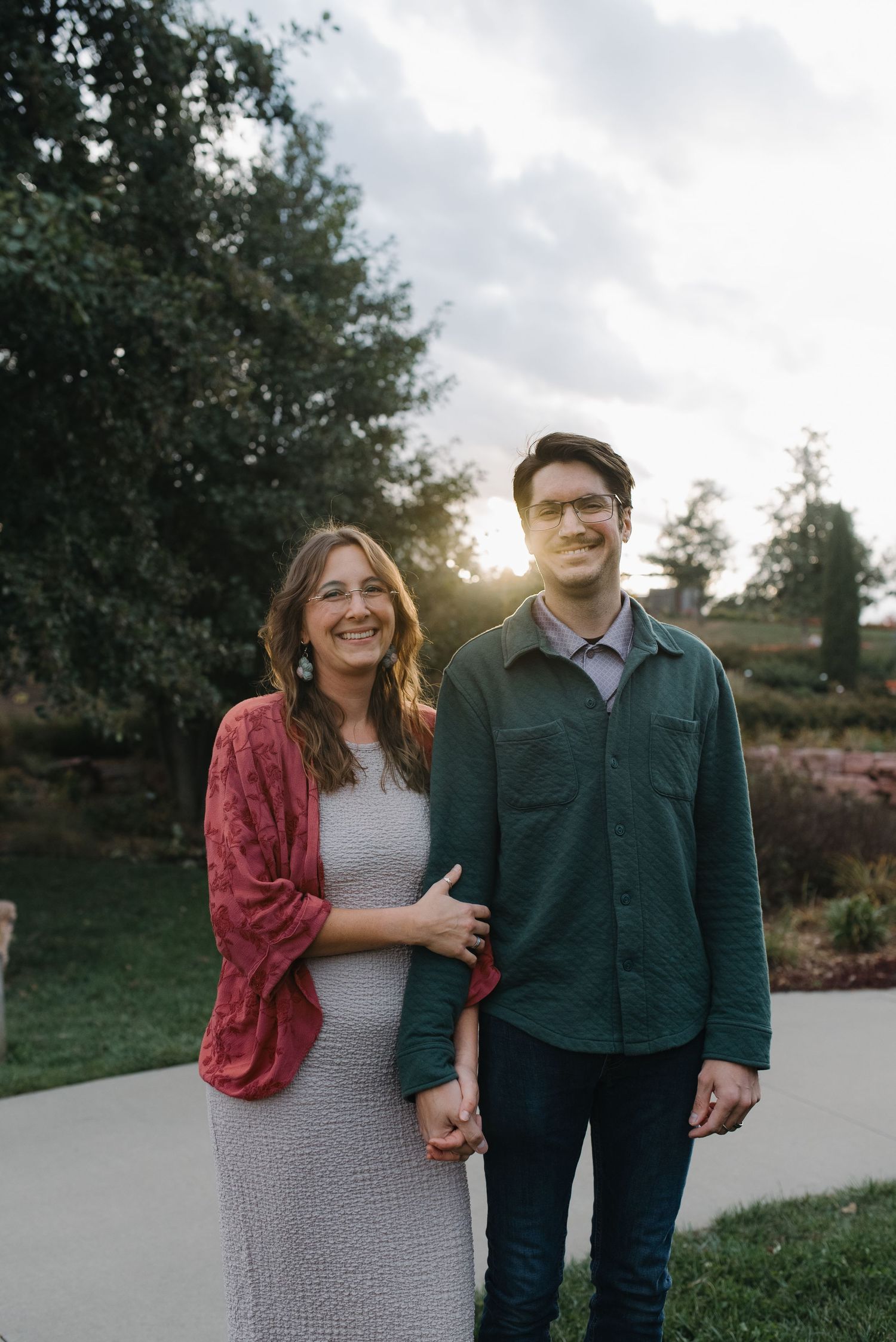 A happy couple holds hands and smiles at sunset in a beautiful garden.