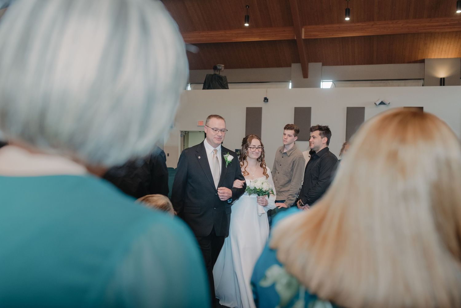 A smiling bride and groom stand at the altar during their indoor wedding ceremony.