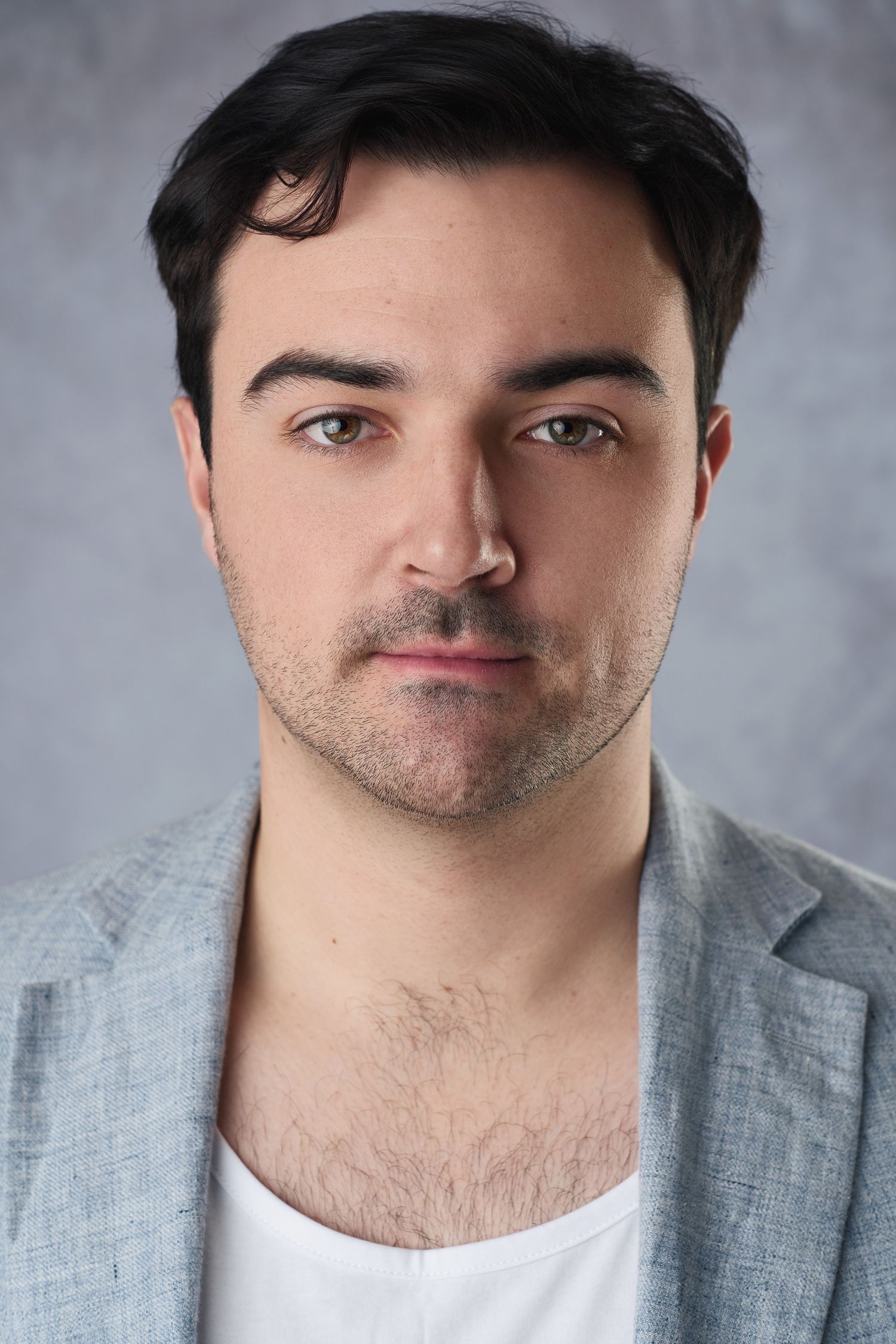Professional headshot portrait of a man wearing a light grey blazer and white shirt against a neutral background.