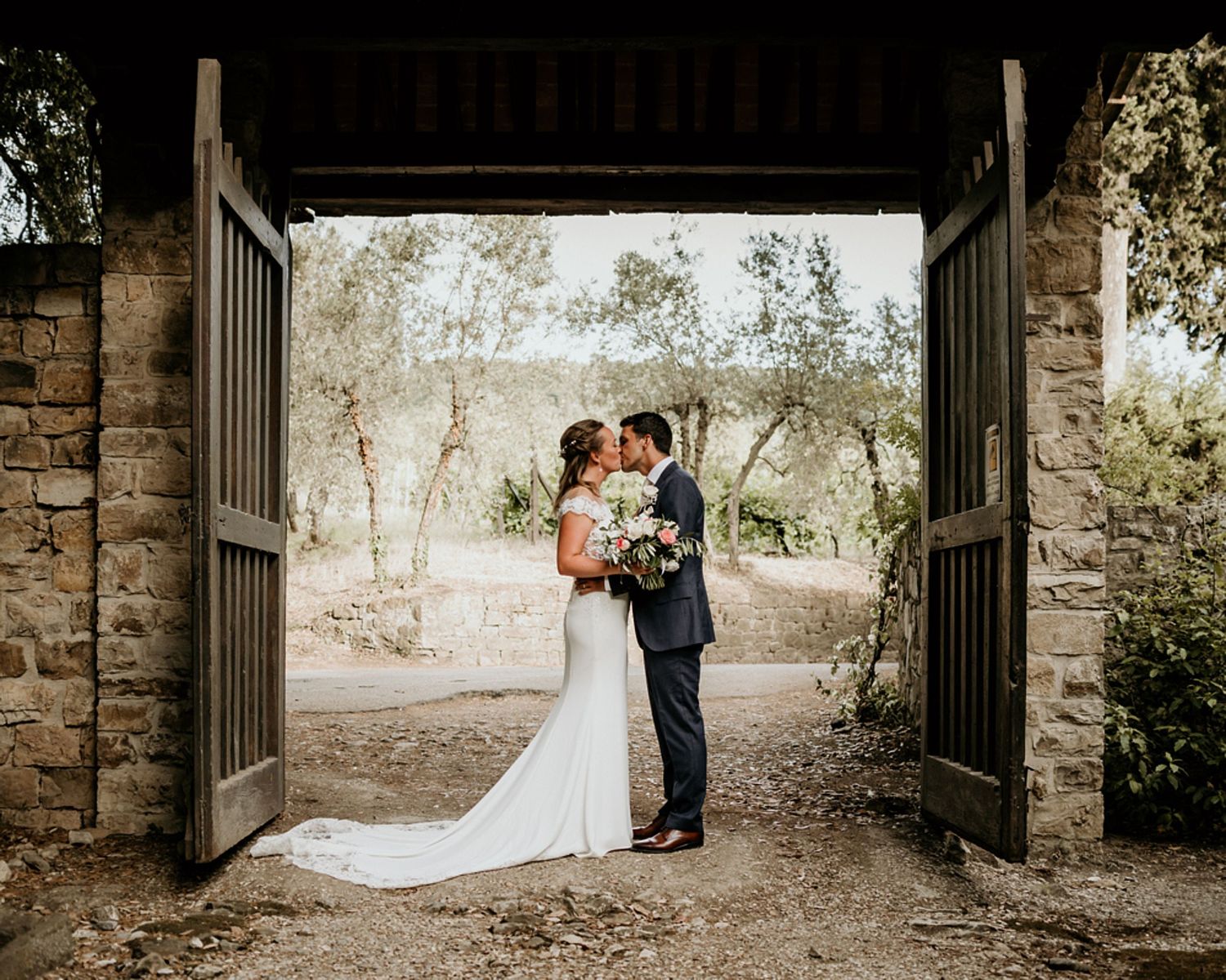 A wedding couple shares romantic moments in a stone archway corridor during their outdoor photo session.