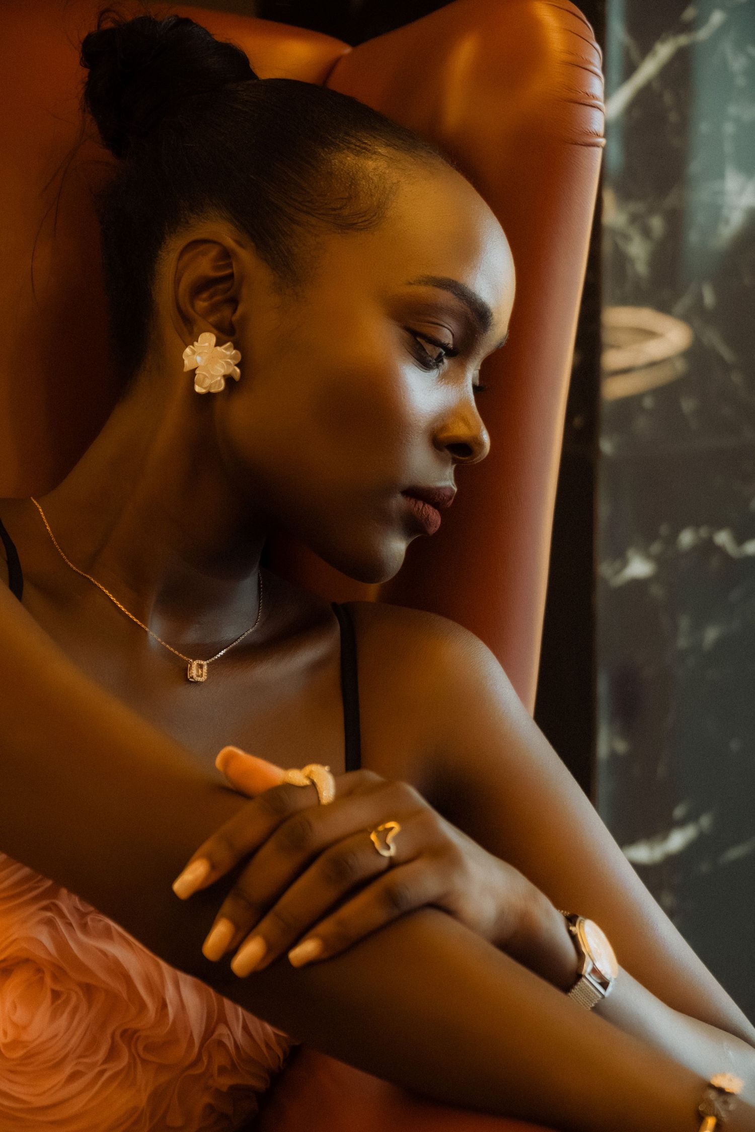 Artistic portrait showing jewelry and flower earring in warm lighting.