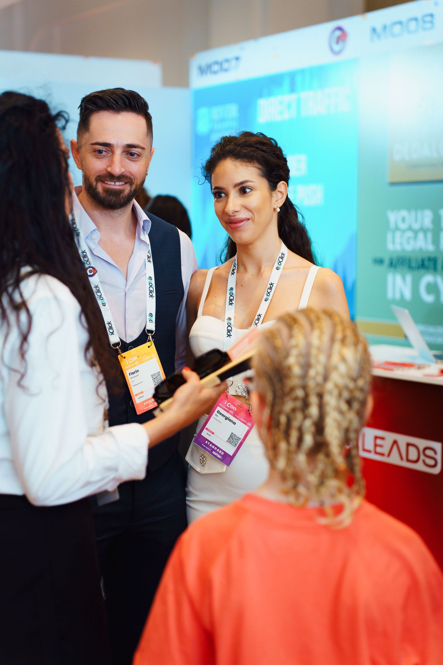 Business professionals networking and having a conversation at a conference booth with banners and marketing displays.