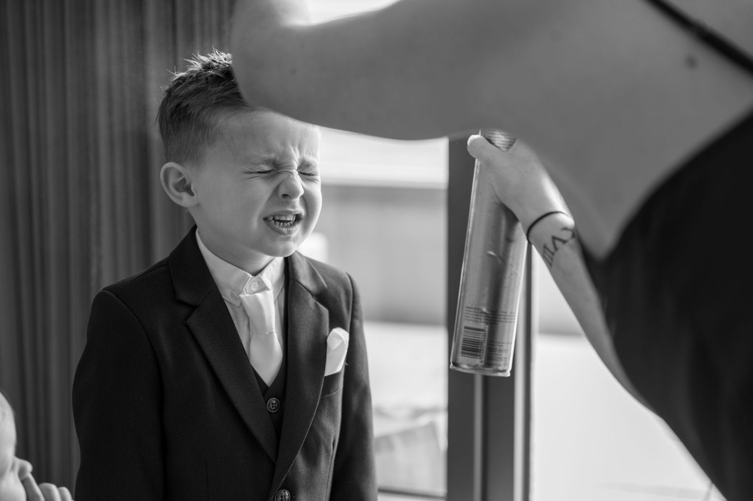 Emotional young boy in suit crying at a wedding ceremony indoor event.