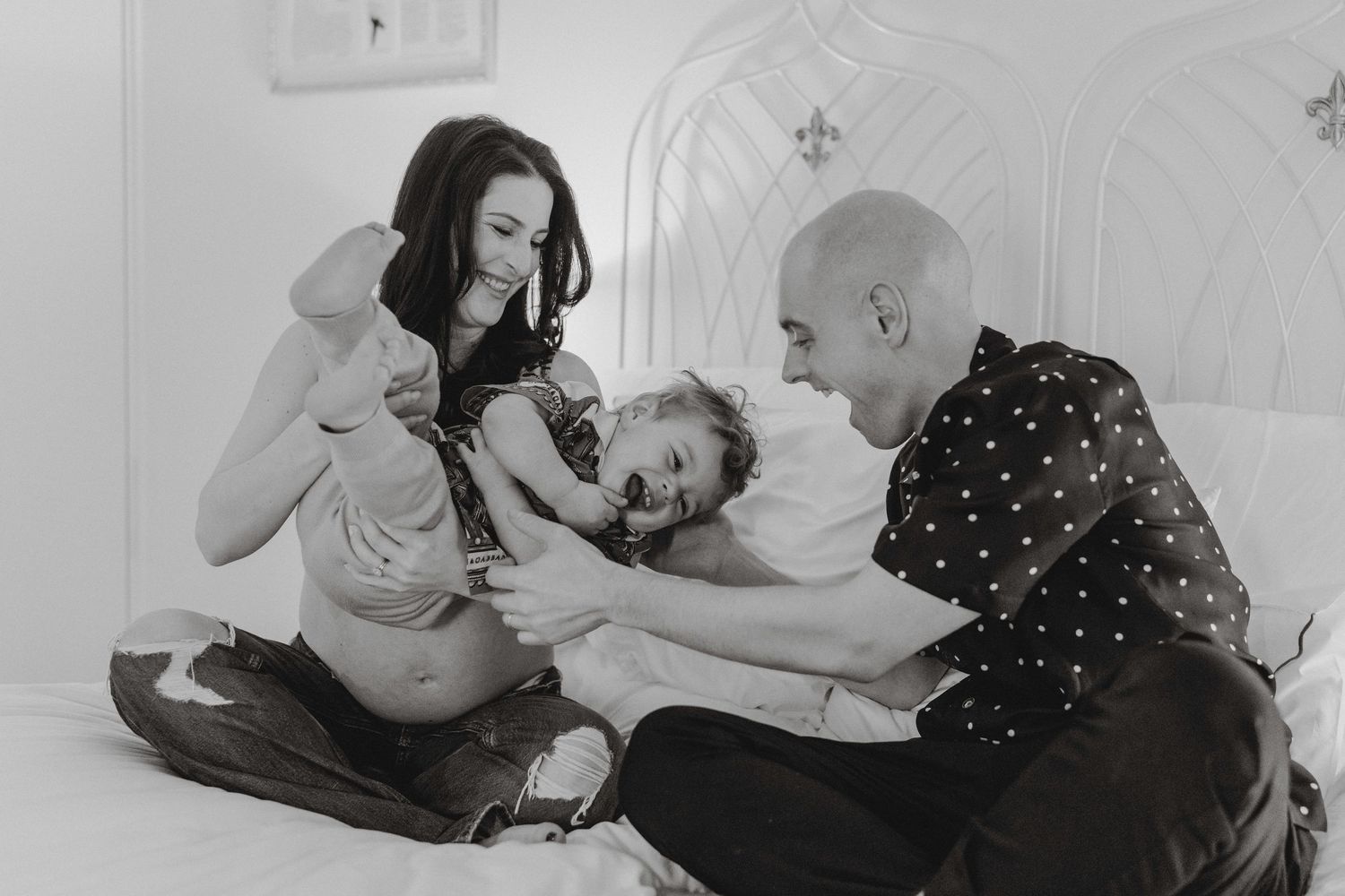 Black and white photo of couple with child on bed.