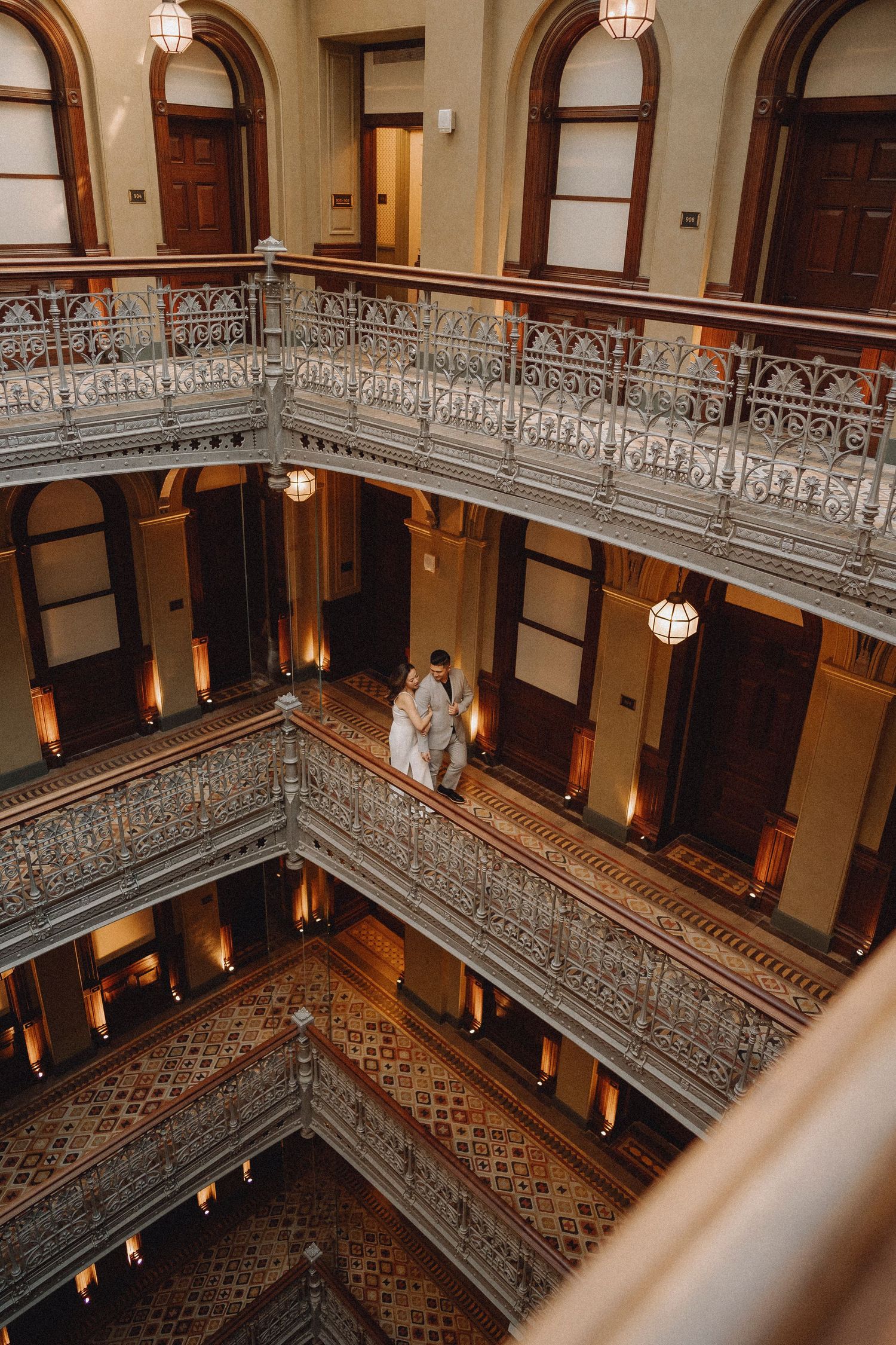 Aerial view of couple standing together on decorative balcony inside a grand historic building.