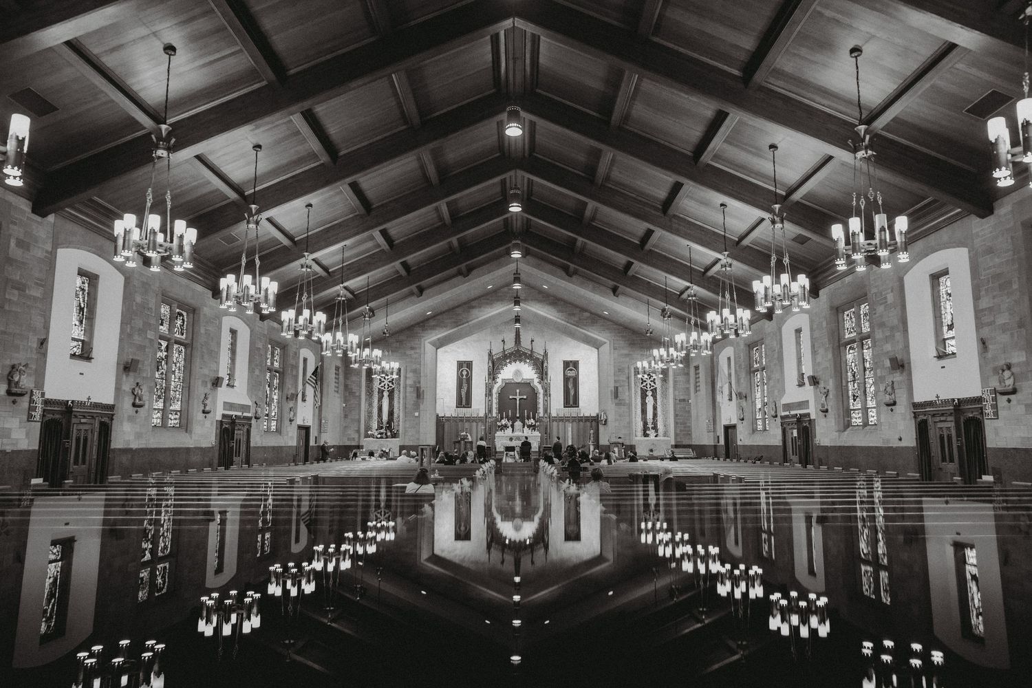Stunning black and white symmetrical view of grand church interior with chandeliers and reflective floor.