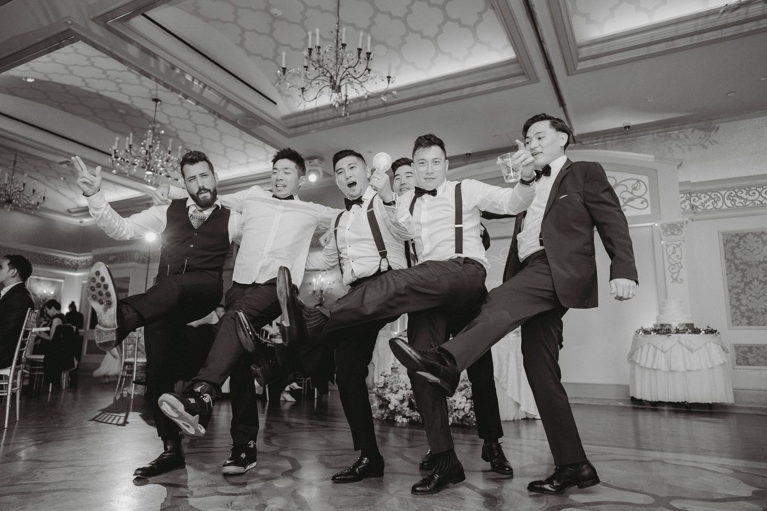 Groom and groomsmen strike a fun energetic pose on the dance floor at wedding reception.