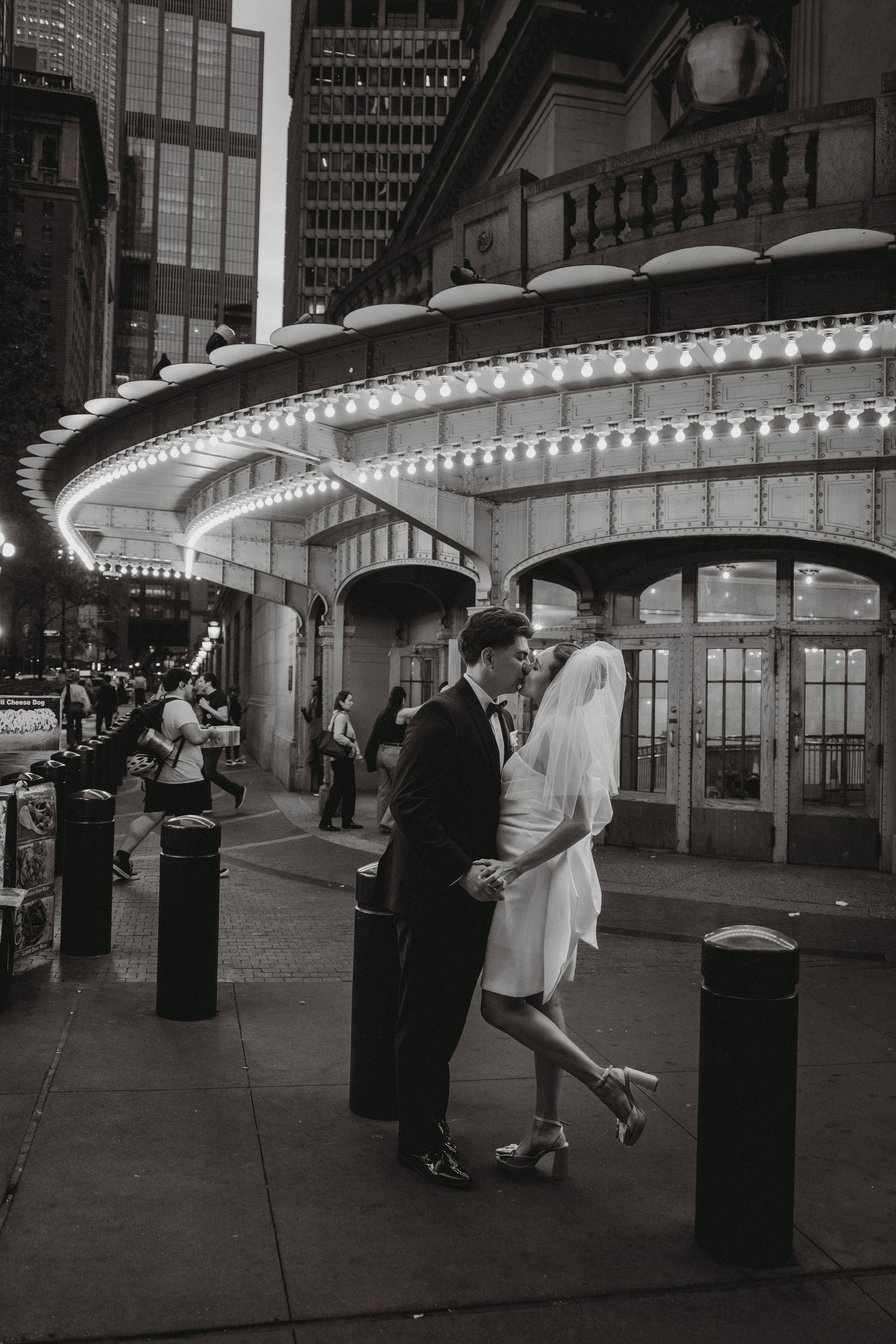 Bride and groom sharing a romantic dance on a city street at night with marquee lights.