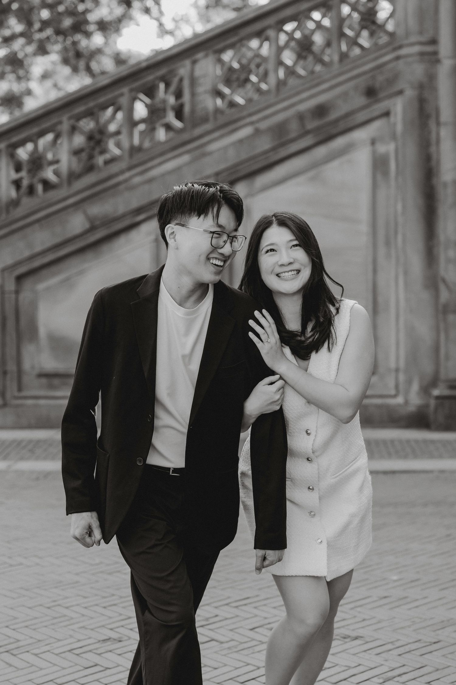 Laughing couple walks arm-in-arm past stone stairs at Bethesda Terrace in Central Park.
