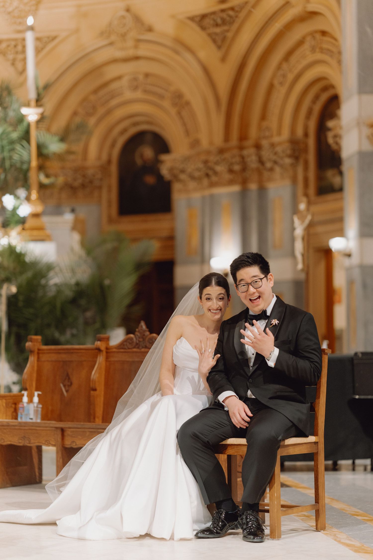 Bride and groom laughing together seated at church altar during wedding ceremony.