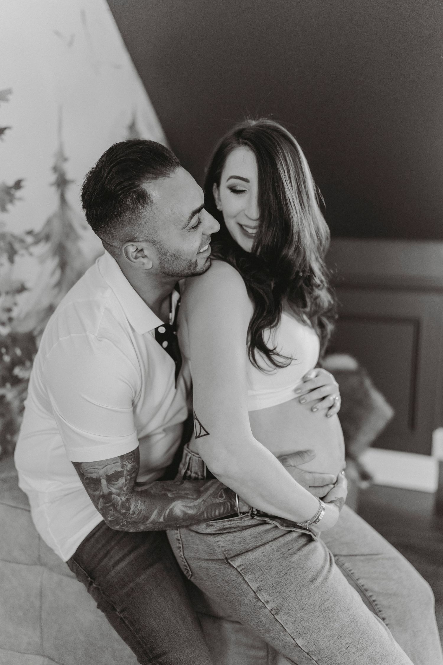 Black and white photo of couple embracing pregnant belly.