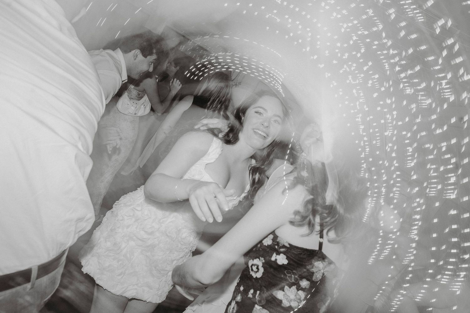 Black and white action shot of bride dancing joyfully at a lively wedding reception celebration.