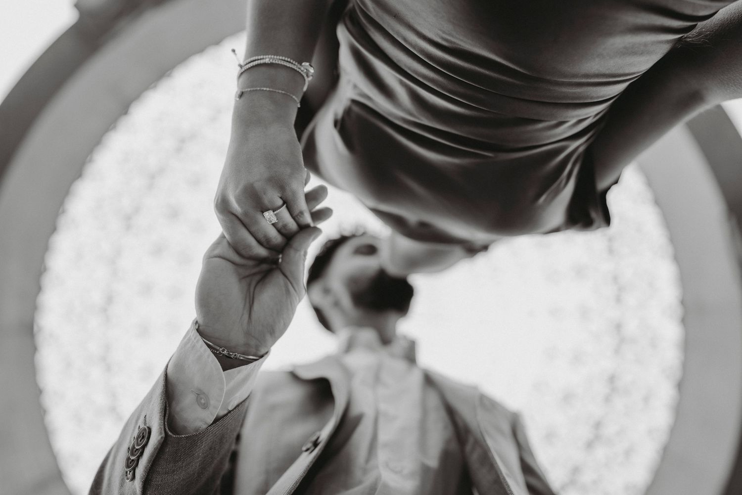 Close-up black and white photo of bride adjusting grooms suit jacket on wedding day.