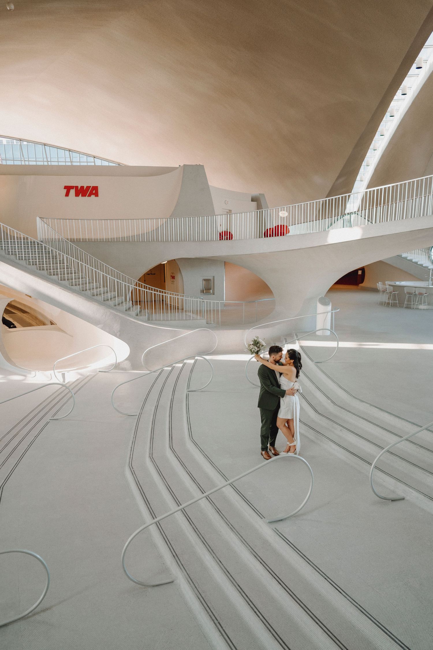 Newlyweds sharing a romantic moment inside the historic TWA Hotel Flight Center at JFK Airport.