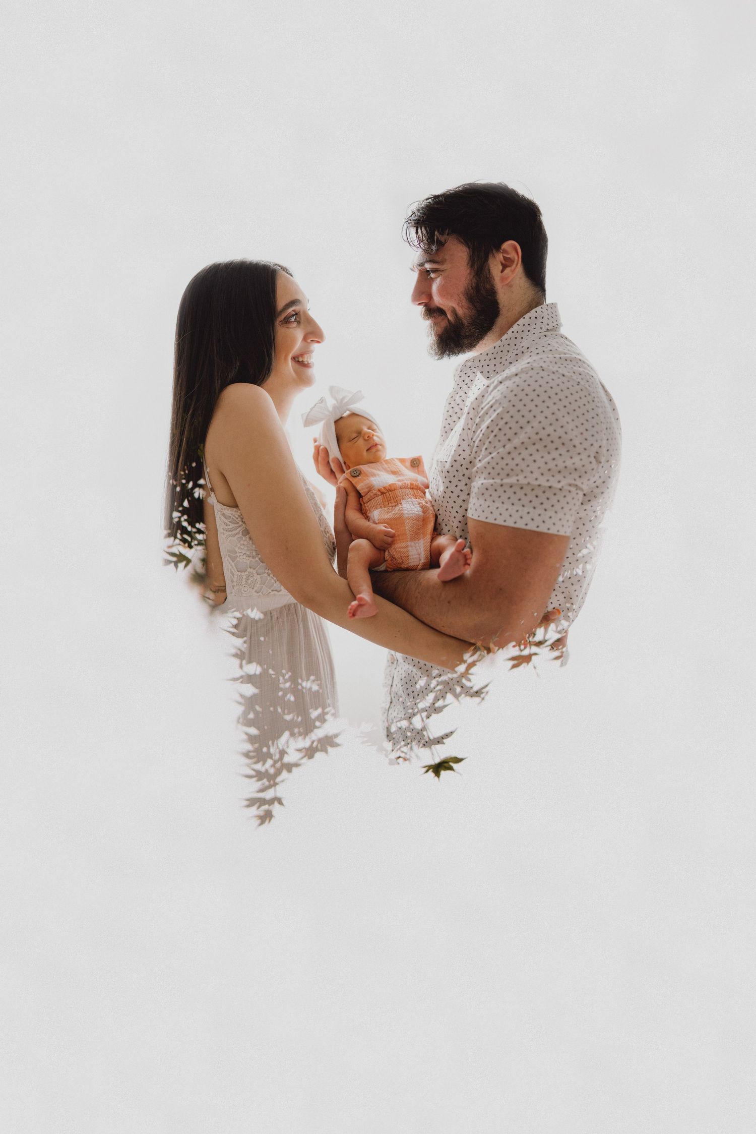 Happy couple smiling at newborn baby with floral double exposure effect.