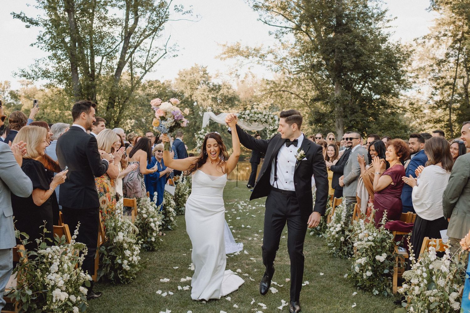 Newlyweds celebrate recessional walk down aisle with cheering guests.