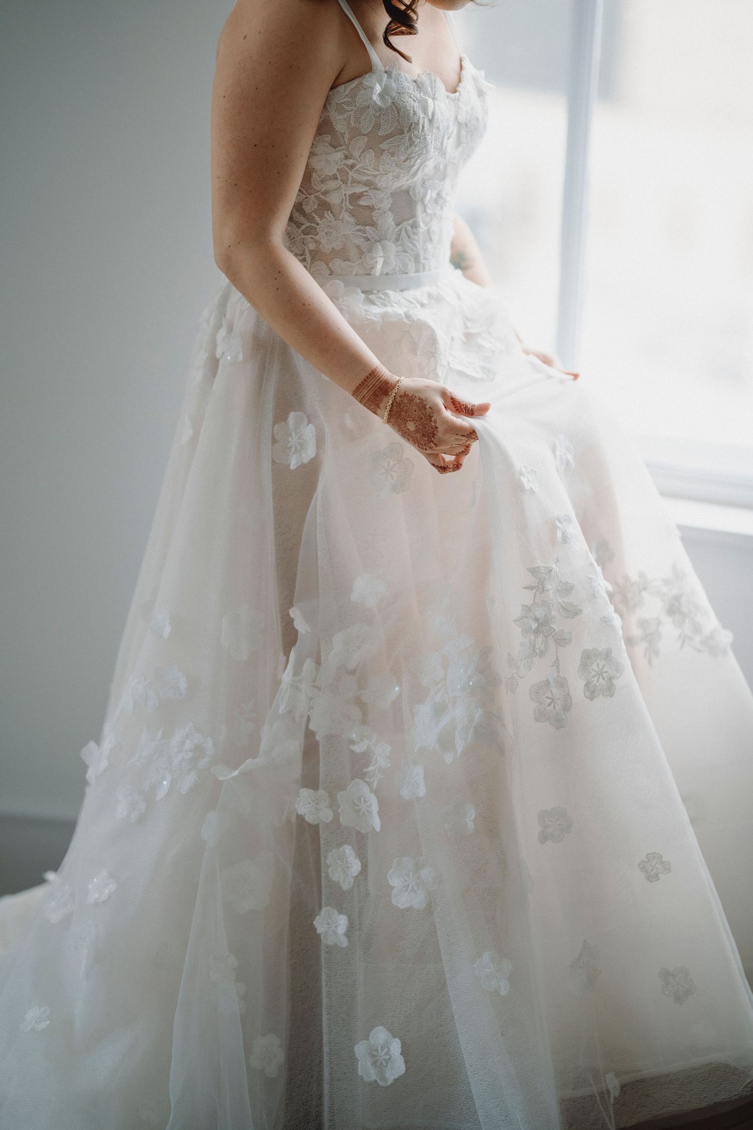 Close-up of bride in strapless floral applique tulle wedding ball gown with henna hands.