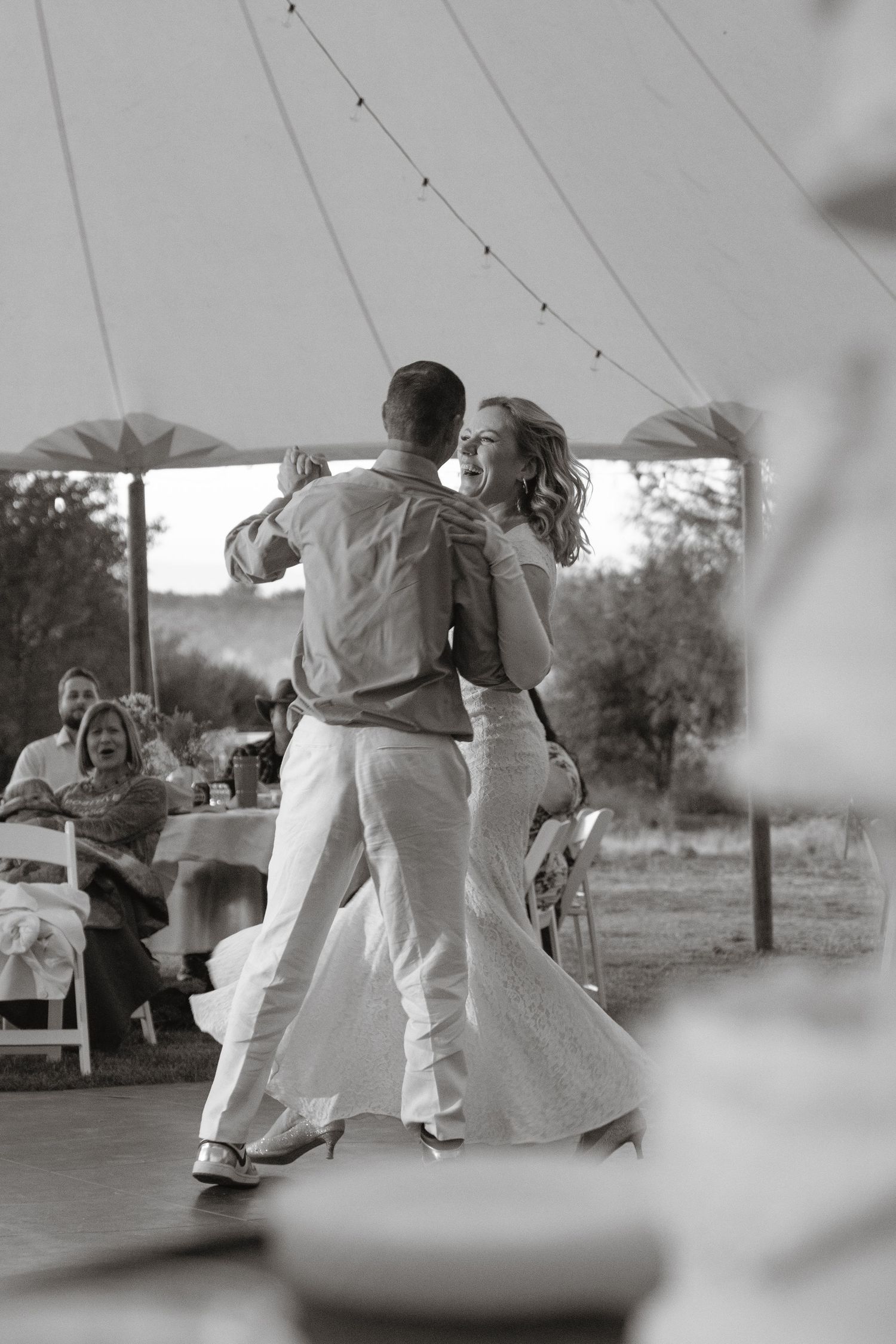 Black and white photo of bride and groom sharing their first dance under a tent at reception in Woodland, CA.
