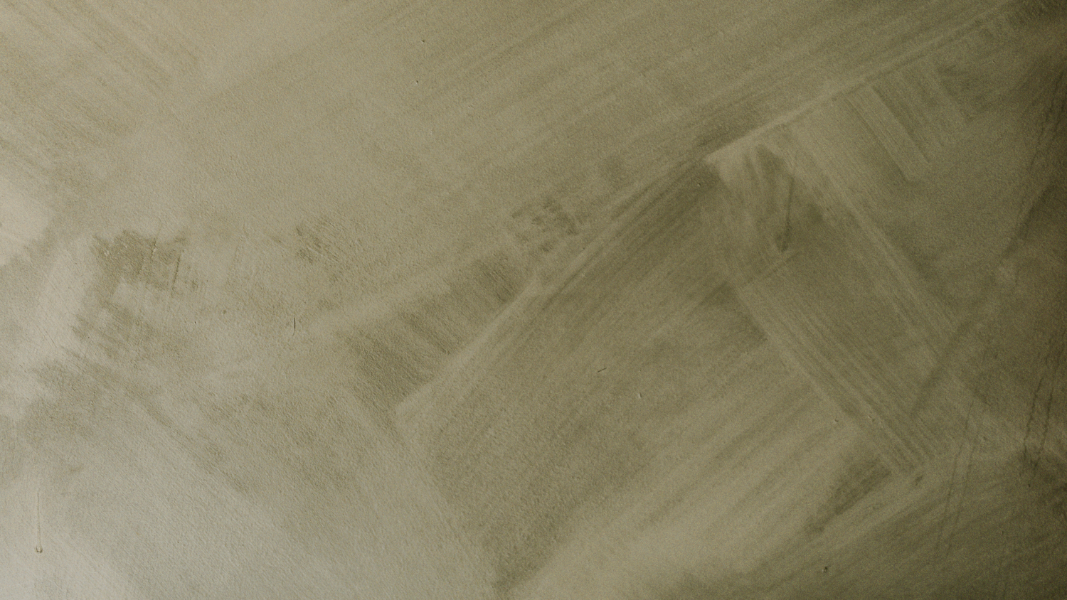 Aerial view of sandy desert terrain with geometric patterns and subtle textures in muted beige tones.